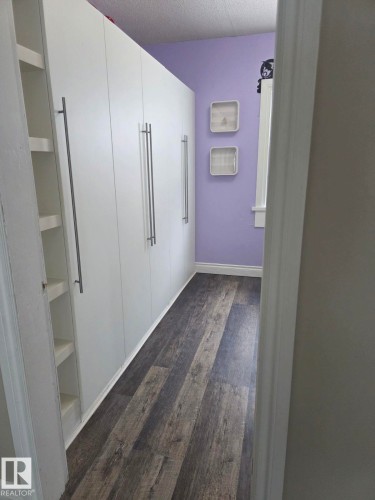 Integrated white cabinetry with elongated silver-tone hardware - 4825 52 Street, Elk Point, AB - Indoor Photo Showing Other Room