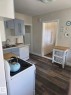 Kitchen featuring wood-finish flooring, light blue upper and lower cabinetry, white subway tile backsplash, and a double basin stainless steel sink. - 4825 52 Street, Elk Point, AB  - Indoor Photo Showing Kitchen With Double Sink 