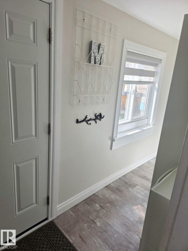 Entryway featuring wood-finish flooring, white paneled door, and neutral wall paint - 4825 52 Street, Elk Point, AB - Indoor Photo Showing Other Room