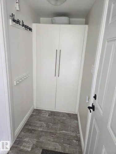 Entryway featuring full-height white cabinetry with vertical bar pulls, grey wood-finish flooring, and white baseboards. - 4825 52 Street, Elk Point, AB - Indoor Photo Showing Other Room