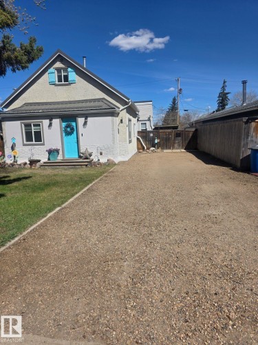 Gray stucco exterior with a contrasting turquoise entry door and matching upper-level shutters. - 4825 52 Street, Elk Point, AB - Outdoor