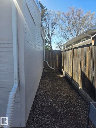 Side yard featuring gravel ground cover and a wood privacy fence. - 4825 52 Street, Elk Point, AB - Outdoor With Exterior