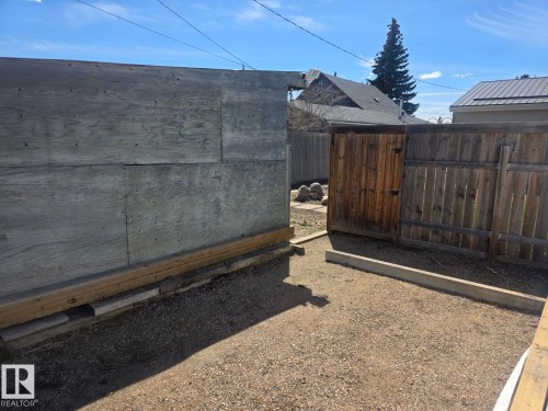 Gravel area with a wood privacy fence and a wooden gate - 4825 52 Street, Elk Point, AB - Outdoor