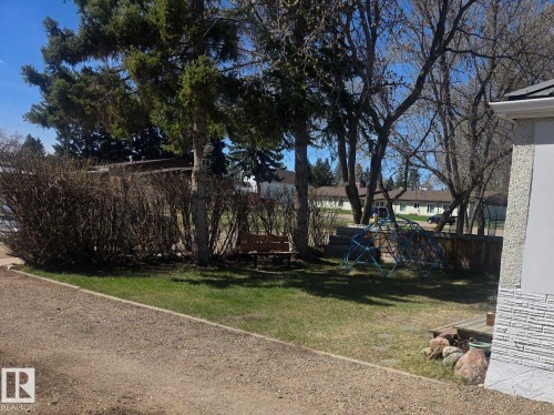 Manicured lawn with mature trees and established shrubbery - 4825 52 Street, Elk Point, AB - Outdoor