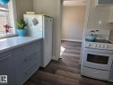 Kitchen featuring slate-blue cabinetry with stainless steel hardware, a light-toned countertop, and wood-finish flooring. - 4825 52 Street, Elk Point, AB  - Indoor Photo Showing Kitchen 