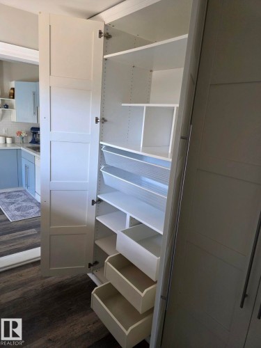 Tall white pantry with adjustable shelving, integrated pull-out drawers, and additional storage bins. - 4825 52 Street, Elk Point, AB - Indoor
