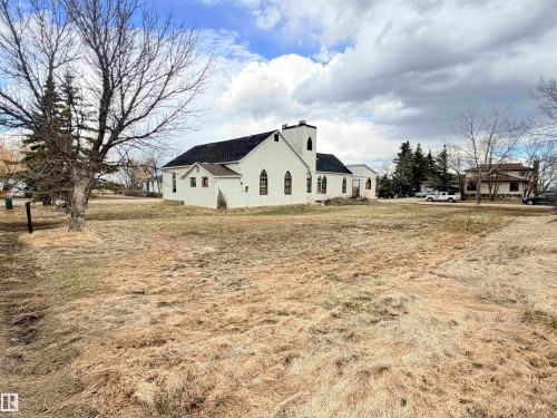 White exterior structure with a dark shingle roof and a prominent steeple feature - 5036 49 Street, Clyde, AB - Outdoor