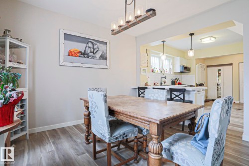 Dining area featuring wood-finish flooring, a rustic linear chandelier, and an open pass-through to the kitchen - 5113 53 Avenue, Stony Plain, AB - Indoor Photo Showing Dining Room
