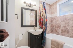 Bathroom with a white soaking tub and brown tiled surround - 