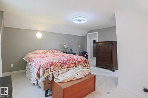 Carpeted room featuring a ceiling-mounted light fixture, wall sconce lighting, and a doorway - 5113 53 Avenue, Stony Plain, AB - Indoor Photo Showing Bedroom