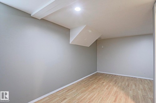 Spacious room featuring wood-finish flooring, light grey painted walls, white baseboards, a flat white ceiling, and recessed lighting - 5113 53 Avenue, Stony Plain, AB - Indoor Photo Showing Other Room