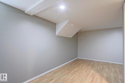 Spacious room featuring wood-finish flooring, light grey painted walls, white baseboards, a flat white ceiling, and recessed lighting - 