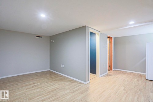 Spacious room featuring light wood-finish flooring, recessed lighting, and neutral grey walls with white trim - 5113 53 Avenue, Stony Plain, AB - Indoor Photo Showing Other Room