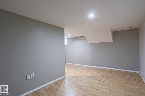 Open-concept room featuring neutral gray walls, light wood-finish flooring, white trim, and recessed ceiling lighting - 5113 53 Avenue, Stony Plain, AB - Indoor Photo Showing Other Room