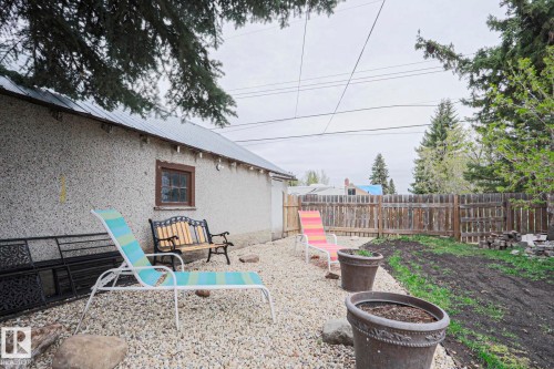 Gravel patio area featuring a stucco exterior structure with a metal roof - 5113 53 Avenue, Stony Plain, AB - Outdoor
