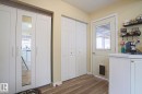 Wood-finish flooring throughout, featuring a white paneled door with glass insert, bi-fold closet doors, built-in shelving, and white cabinetry with a light-toned countertop - 5113 53 Avenue, Stony Plain, AB  - Indoor Photo Showing Other Room 