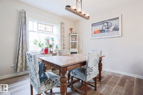 Dining area featuring wood-finish flooring, a white window frame, and a stained-glass accent - 5113 53 Avenue, Stony Plain, AB - Indoor Photo Showing Dining Room