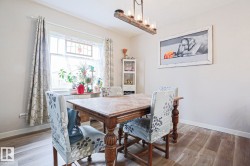 Dining area featuring wood-finish flooring, a white window frame, and a stained-glass accent - 