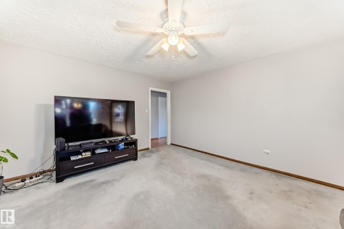 Carpeted interior space featuring light gray walls, a textured ceiling, and a ceiling fan with integrated lighting - 9716 162 Street, Edmonton, AB - Indoor