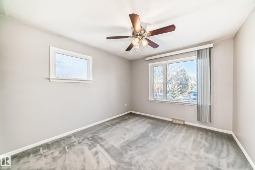 Room featuring neutral wall tones, gray patterned carpeting, a multi-pane window with vertical blinds, a smaller frosted window, and a ceiling fan with light fixture - 9716 162 Street, Edmonton, AB - Indoor Photo Showing Other Room