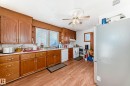 Kitchen featuring wood-finish flooring, wood cabinetry with gold-tone hardware, white countertops, and a white dishwasher - 9716 162 Street, Edmonton, AB  - Indoor Photo Showing Kitchen With Double Sink 