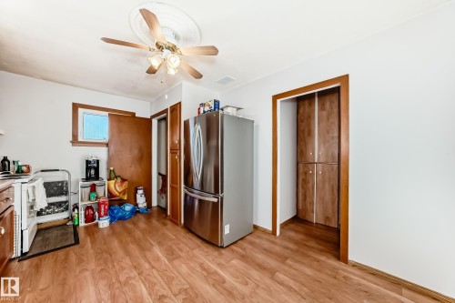 Kitchen space featuring wood-finish flooring, a stainless steel refrigerator, white walls, and a ceiling fan with light fixture - 9716 162 Street, Edmonton, AB - Indoor