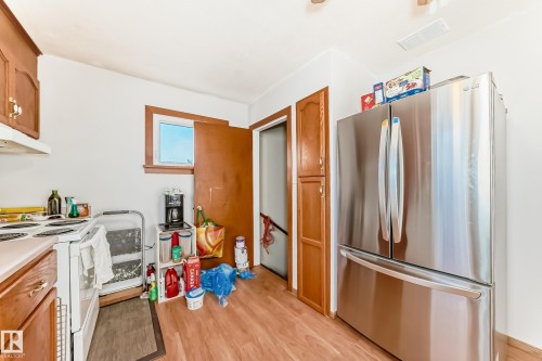 Kitchen featuring wood-finish flooring, a stainless steel French door refrigerator, wood cabinetry, and a window with wood trim - 9716 162 Street, Edmonton, AB - Indoor Photo Showing Kitchen