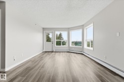 Spacious room featuring wood-finish flooring, light grey walls, and a textured white ceiling - 