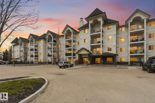 Multi-story residential building featuring a light-colored stucco exterior with dark-pitched roofs - 407 13635 34 Street Nw, Edmonton, AB - Outdoor With Balcony With Facade