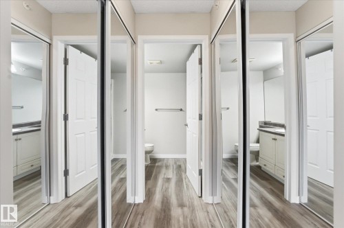 Hallway featuring wood-finish flooring, mirrored closet doors, and recessed lighting - 407 13635 34 Street Nw, Edmonton, AB - Indoor