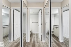 Hallway featuring wood-finish flooring, mirrored closet doors, and recessed lighting - 