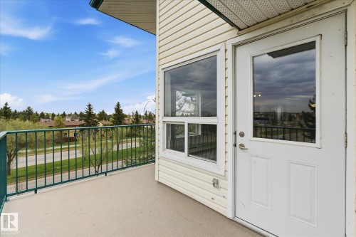 Outdoor balcony with a pale concrete surface, featuring a green metal railing and white siding - 407 13635 34 Street Nw, Edmonton, AB - Outdoor With Exterior