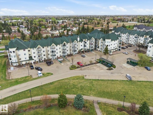 Multi-story residential complex featuring white siding and green hip roofs - 407 13635 34 Street Nw, Edmonton, AB - Outdoor With View
