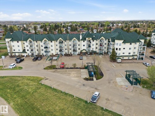 Multi-story residential building featuring light-toned exterior siding and dark green roofing - 407 13635 34 Street Nw, Edmonton, AB - Outdoor With View
