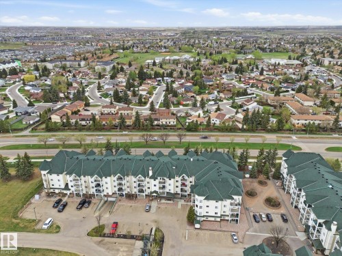 Multi-story residential complex featuring white siding and dark green roofing - 407 13635 34 Street Nw, Edmonton, AB - Outdoor With View
