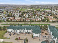 Multi-story residential complex featuring white siding and dark green roofing - 