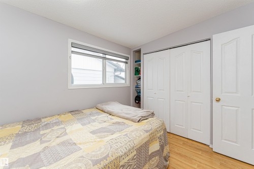 Room featuring light-toned walls, wood-finish flooring, a window with roller blinds, and white bi-fold closet doors - 10412 39 Avenue, Edmonton, AB - Indoor Photo Showing Bedroom