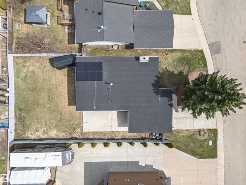 Property featuring a dark shingle roof with solar panels, an elongated driveway, and a spacious rear yard - 10412 39 Avenue, Edmonton, AB - 