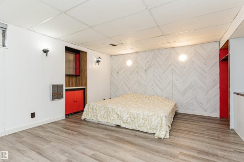 Spacious room featuring wood-finish flooring and a distinctive white chevron accent wall - 10412 39 Avenue, Edmonton, AB - Indoor Photo Showing Bedroom