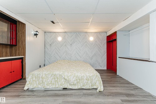 Spacious room featuring wood-finish flooring, a decorative accent wall, and recessed ceiling with paneling - 10412 39 Avenue, Edmonton, AB - Indoor Photo Showing Bedroom