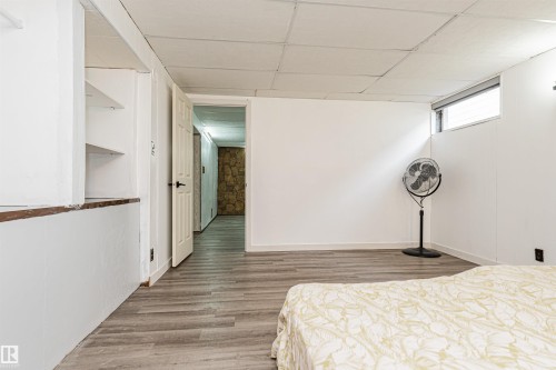Room featuring wood-finish flooring, white walls, and a drop-tile ceiling - 10412 39 Avenue, Edmonton, AB - Indoor