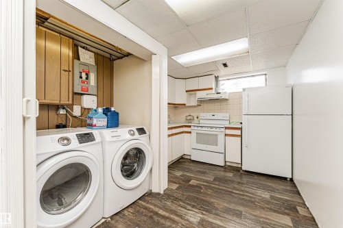 Laundry area and kitchen featuring white appliances, wood-finish flooring, white cabinetry, and a drop ceiling with fluorescent lighting - 10412 39 Avenue, Edmonton, AB - Indoor Photo Showing Laundry Room