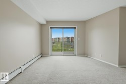 Light-filled room featuring neutral wall paint, light-colored carpeting, and a sliding glass door leading to a private balcony - 
