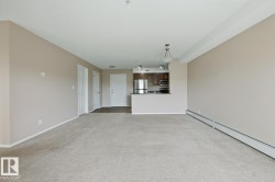 Open-concept living space featuring neutral carpet flooring and light beige walls - 