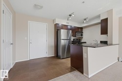Kitchen area featuring dark wood-finish cabinetry, stainless steel appliances, and a dark countertop breakfast bar - 