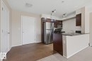 Kitchen area featuring dark wood-finish cabinetry, stainless steel appliances, and a dark countertop breakfast bar - 303 11804 22 Avenue, Edmonton, AB  - Indoor Photo Showing Kitchen 