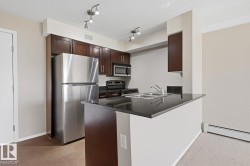 Kitchen featuring stainless steel appliances, dark wood cabinetry, and track lighting - 