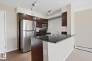 Kitchen featuring stainless steel appliances, dark wood cabinetry, and track lighting - 303 11804 22 Avenue, Edmonton, AB  - Indoor Photo Showing Kitchen With Double Sink 