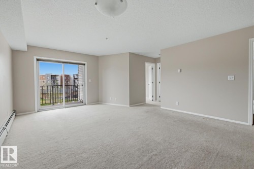 Spacious room featuring neutral carpeting and light-toned walls - 303 11804 22 Avenue, Edmonton, AB - Indoor Photo Showing Other Room