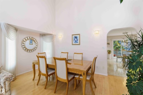 This dining area features light hardwood flooring, high ceilings, and an arched entryway - #1 Colonial Close, Beaumont, AB - Indoor Photo Showing Dining Room